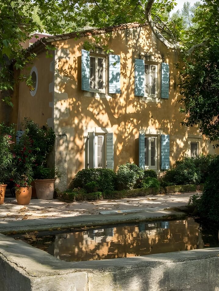 Baumaniere hotel in Provence, France surrounded by trees and a garden pond.