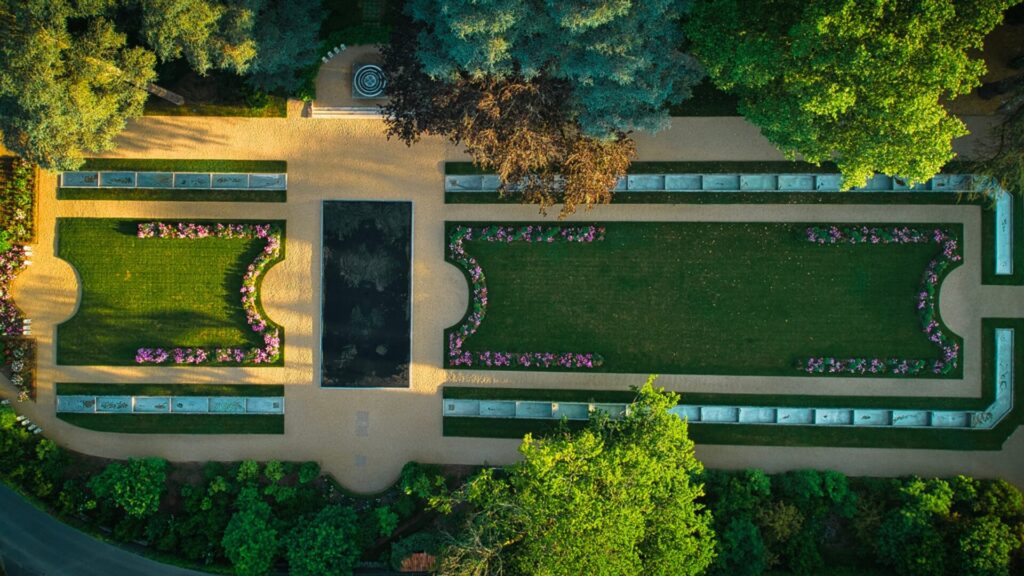 Bird’s eye view of a sprawling Dordogne garden lined with purple flowers and a walking path.