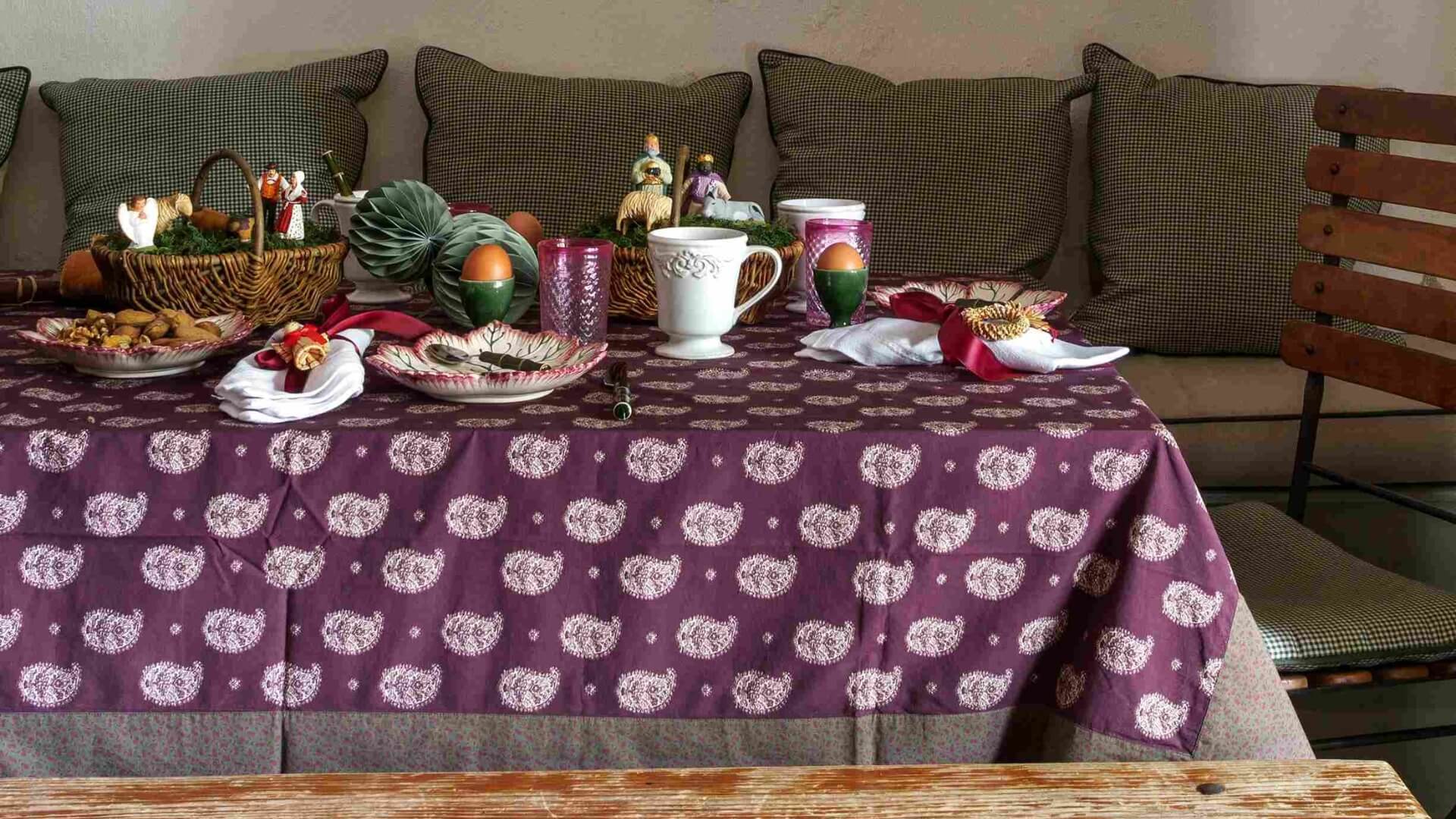 At Le Château de ma Mère in Provence, a table is set with purple linens, glassware, and unique French dishes.
