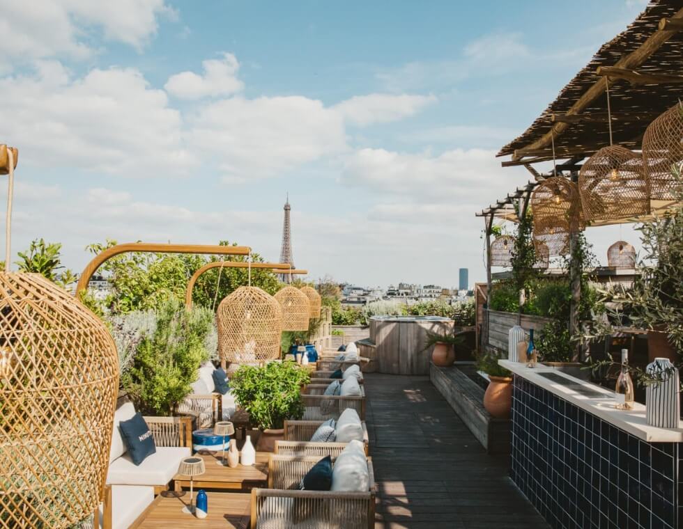 Brach's summery, Parisian, rooftop terrace and bar framed with greenery and climbing vines.