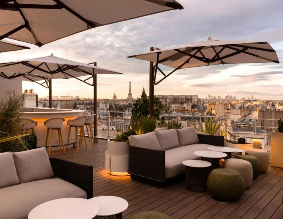 Rooftop lounge in Paris with plush seating, low lighting, and large umbrellas.