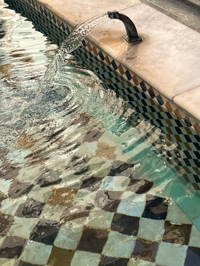 Clear water flowing through a tiled stone pool.