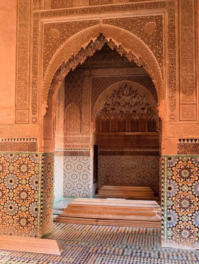 Ornate Moroccan doorway with mosaic-tiled floor and walls.