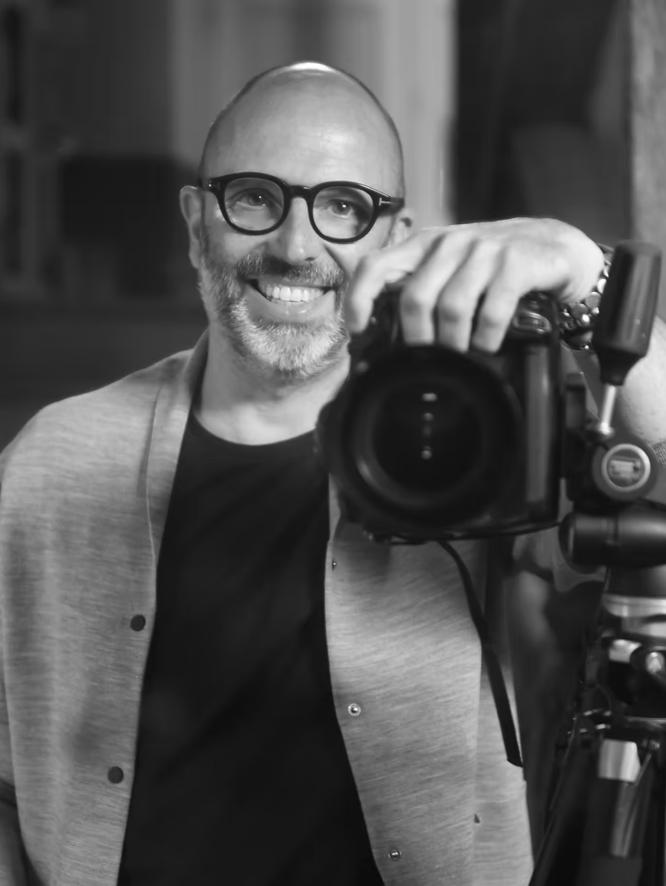 Man smiling while posing with a camera.