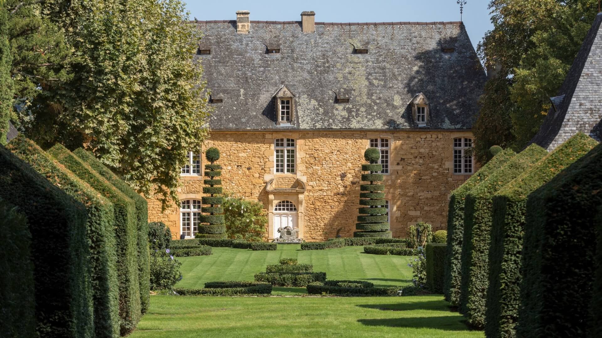 A historic Dordogne estate surrounded by towering, design crafted hedges.