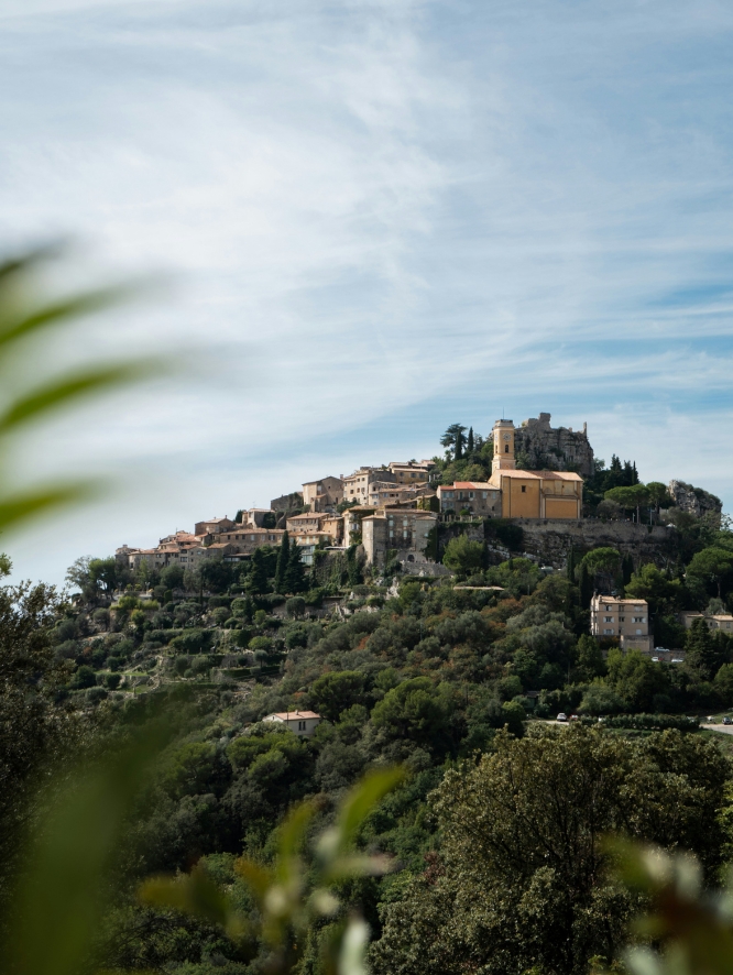 French Riviera commune Èze on a tall, lush mountain against a summery blue sky.