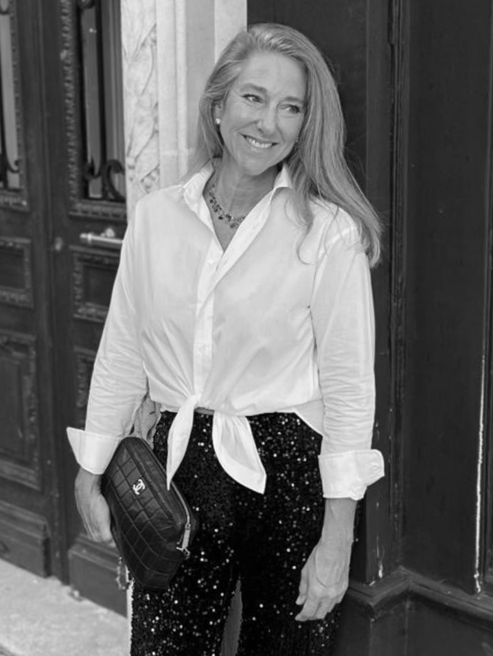 Portrait of a blond woman smiling while leaning against a wall.