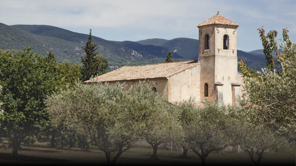 A provincial chapel nestled between hills and an olive grove.