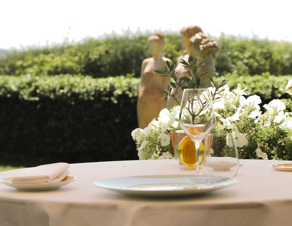 La Bastide Saint-Antoine on the French Riviera offers outdoor garden dining surrounded by statues, lush hedges, and flowers.