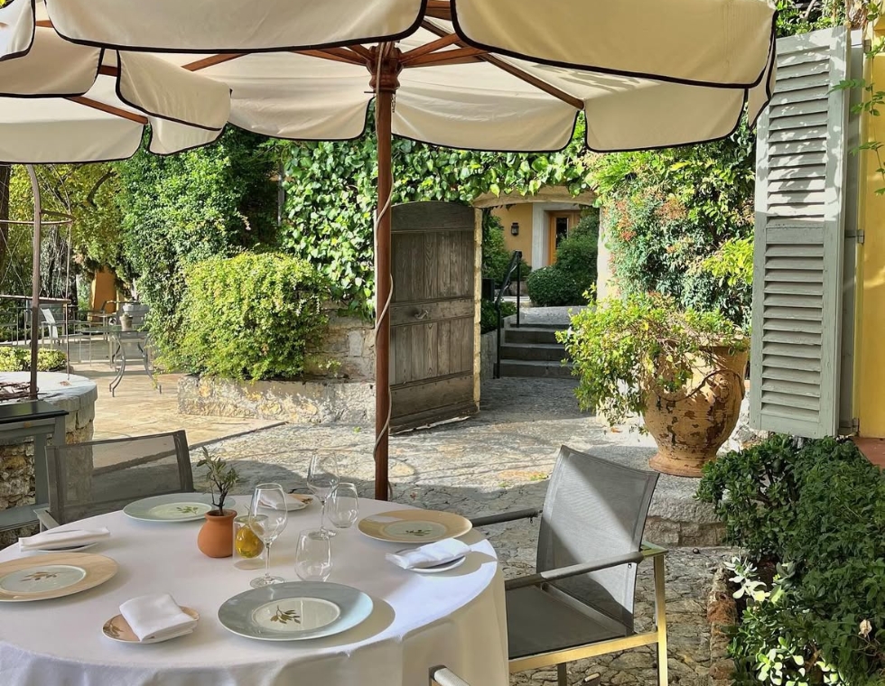 An ivy-covered entrance to La Bastide Saint-Antoine’s garden dining area with shaded outdoor seating.