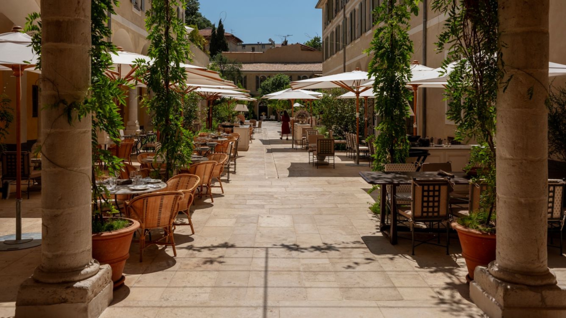 Le Couvent’s sun drenched private terrace is dotted with wicker chairs, shaded by tall white umbrellas, and framed by hanging vines.