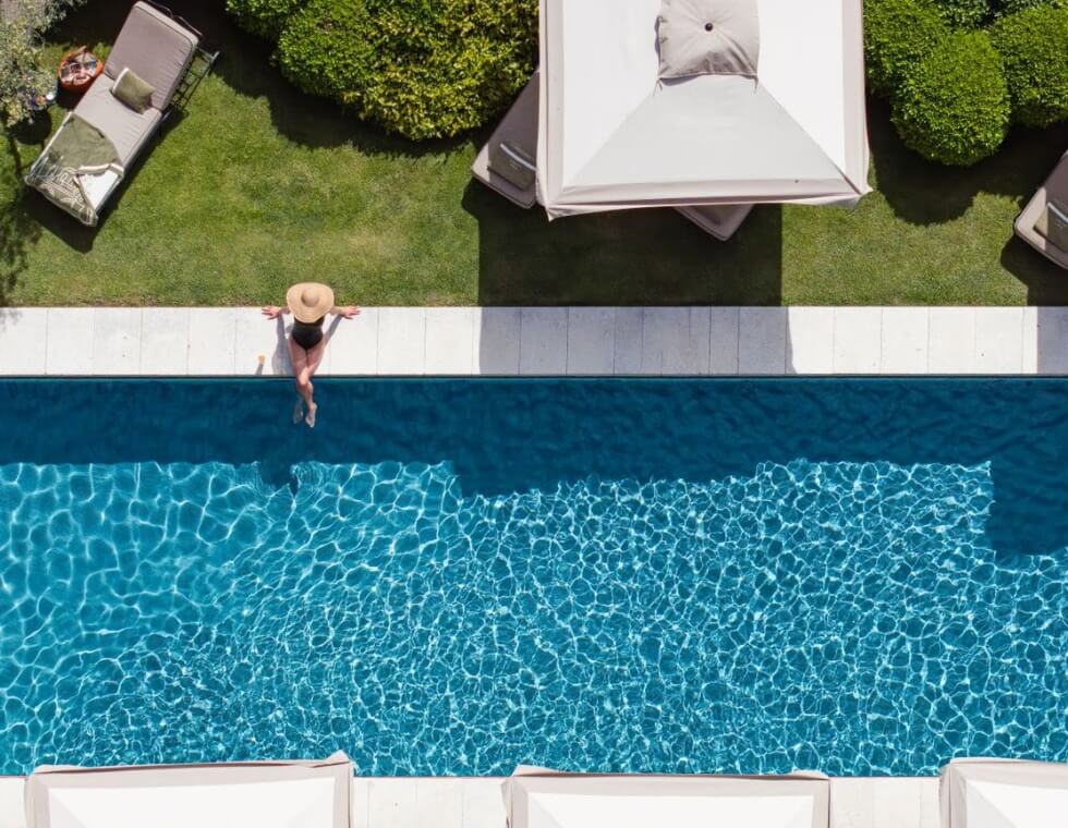 Aerial view of the luxury swimming pool at Bastide de Gordes in Provence, with a sunbather relaxing at the water's edge.