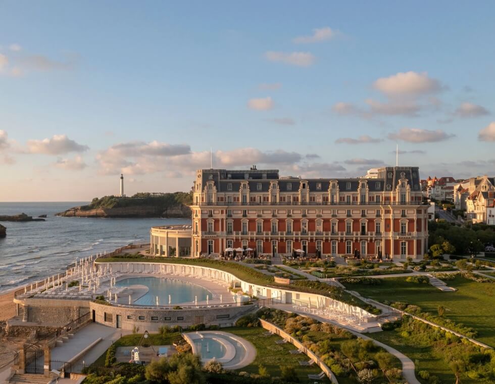 Hotel du Palais's estate features a pool and jacuzzi, neatly placed between lush grassy grounds and the rocky coast.