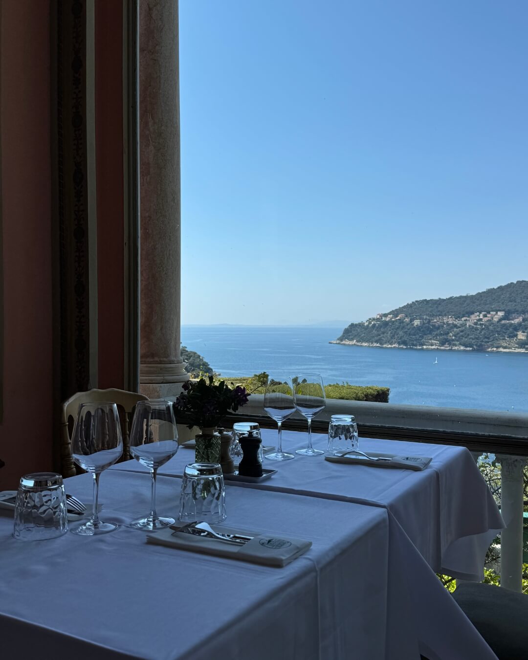 French Riviera restaurant set for service, overlooking the mountainous coast line of the Mediterranean Sea.