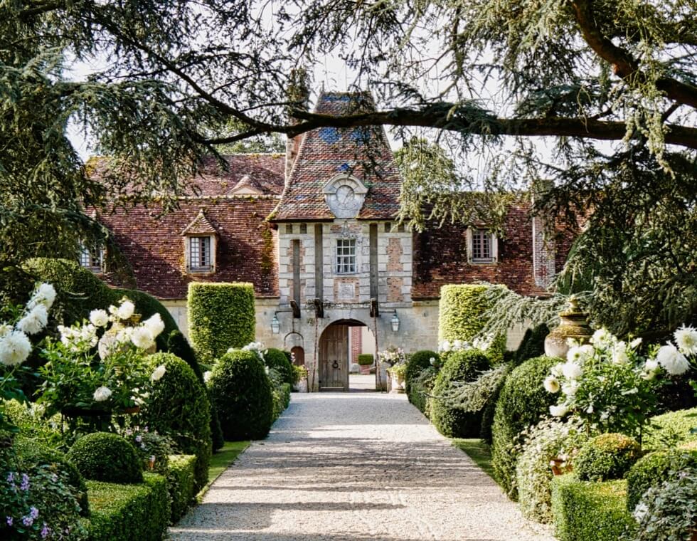 Boutemont Castle’s lush green hedges and blooming white flowers line the walking paths through the estate grounds.