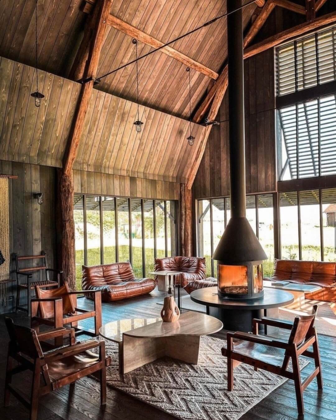 Rustic French Cheverny home filled with natural light, cozy seating around the fire, and warm wooden paneling.