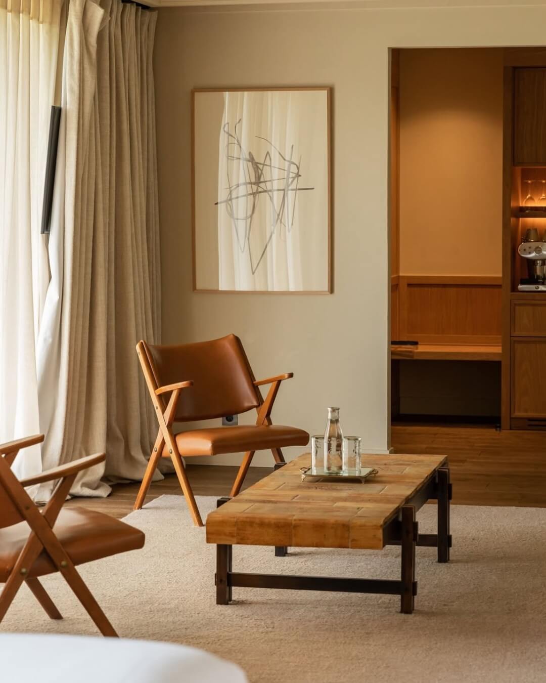 Home in Cheverny, France is decorated with warm, minimalist, leather chairs, art, and a coffee table.