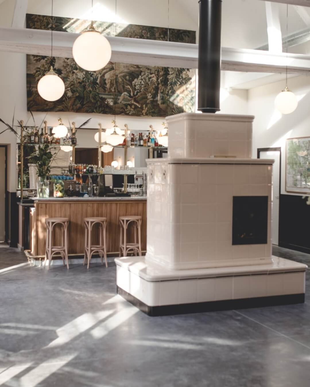 Le Barn's minimalist style bar features a woven tapestry, ceramic fire place, and elegant pendant lighting.