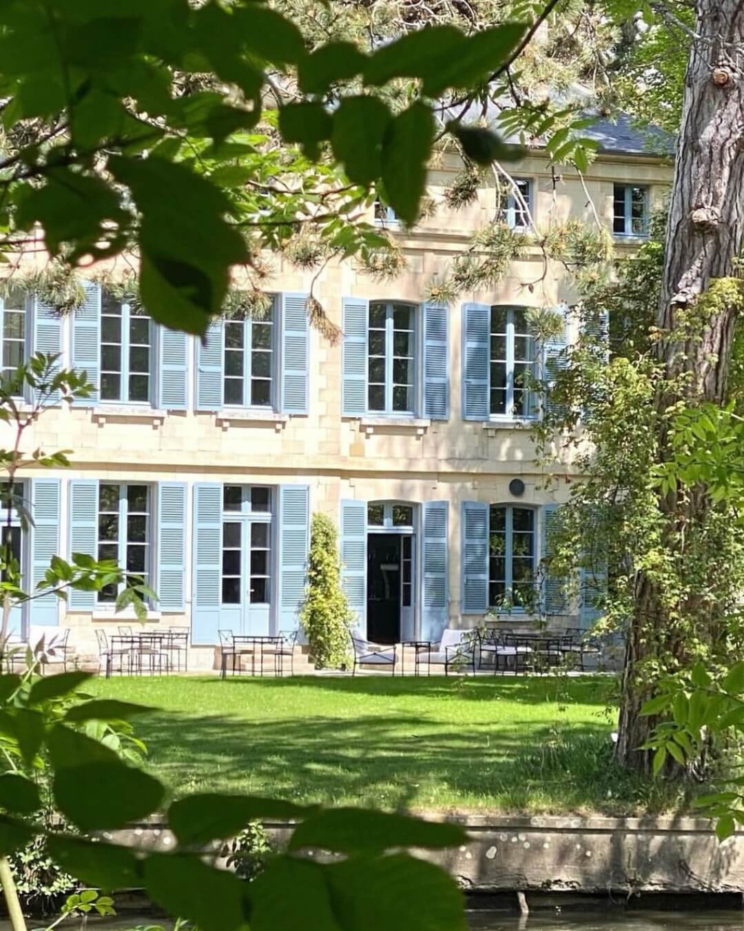 Domaine de Primard’s estate features grand French windows, blue shutters, and lush green grounds.