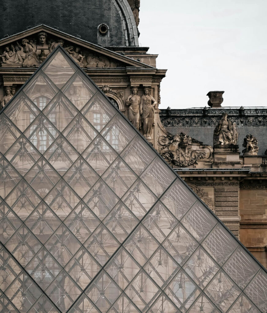 View of the historic Louvre Museum facade framed by the iconic I.M. Pei glass pyramid in Paris, France.