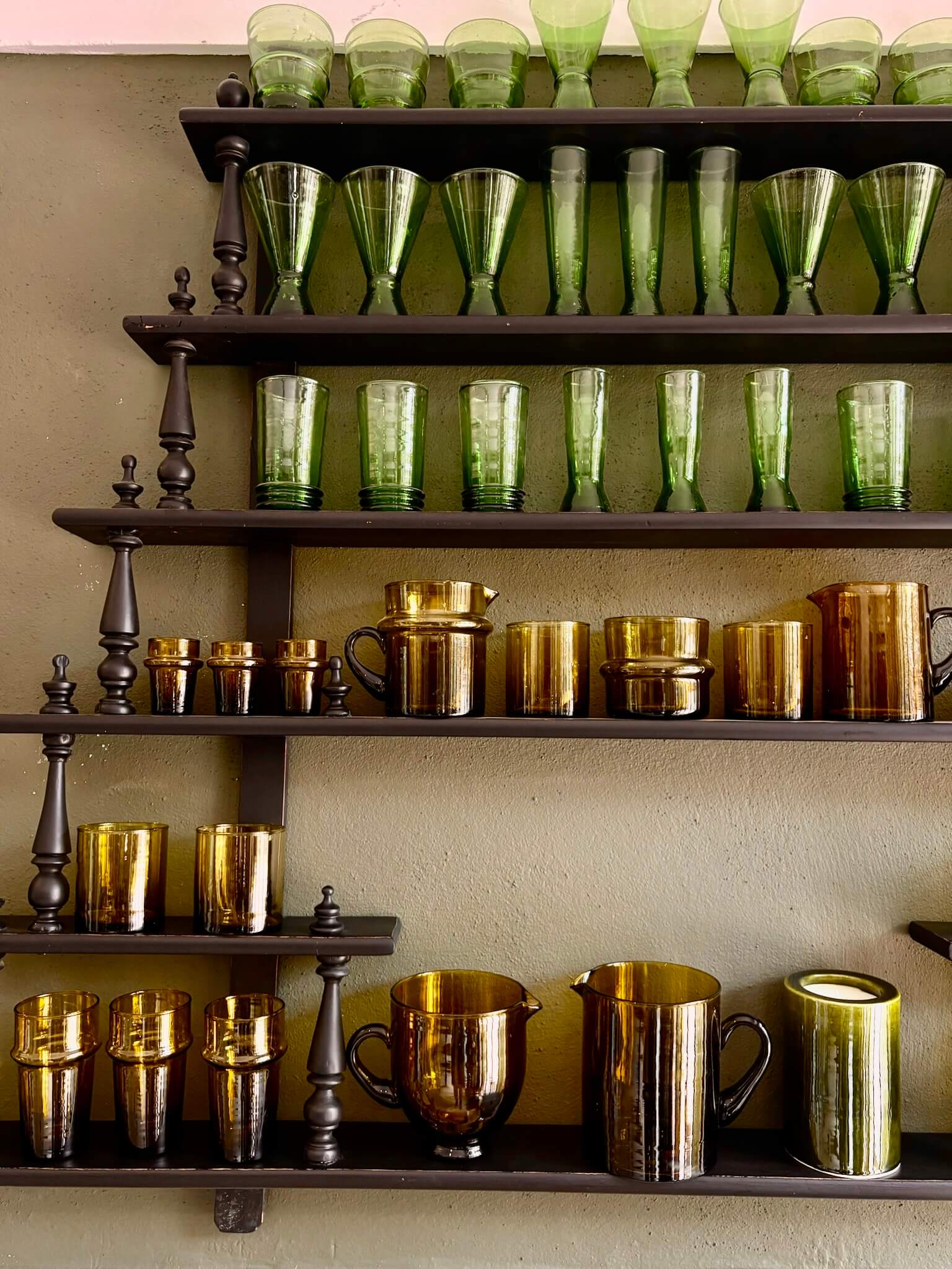 Elegantly crafted amber and green glasses placed on a wooden shelf.