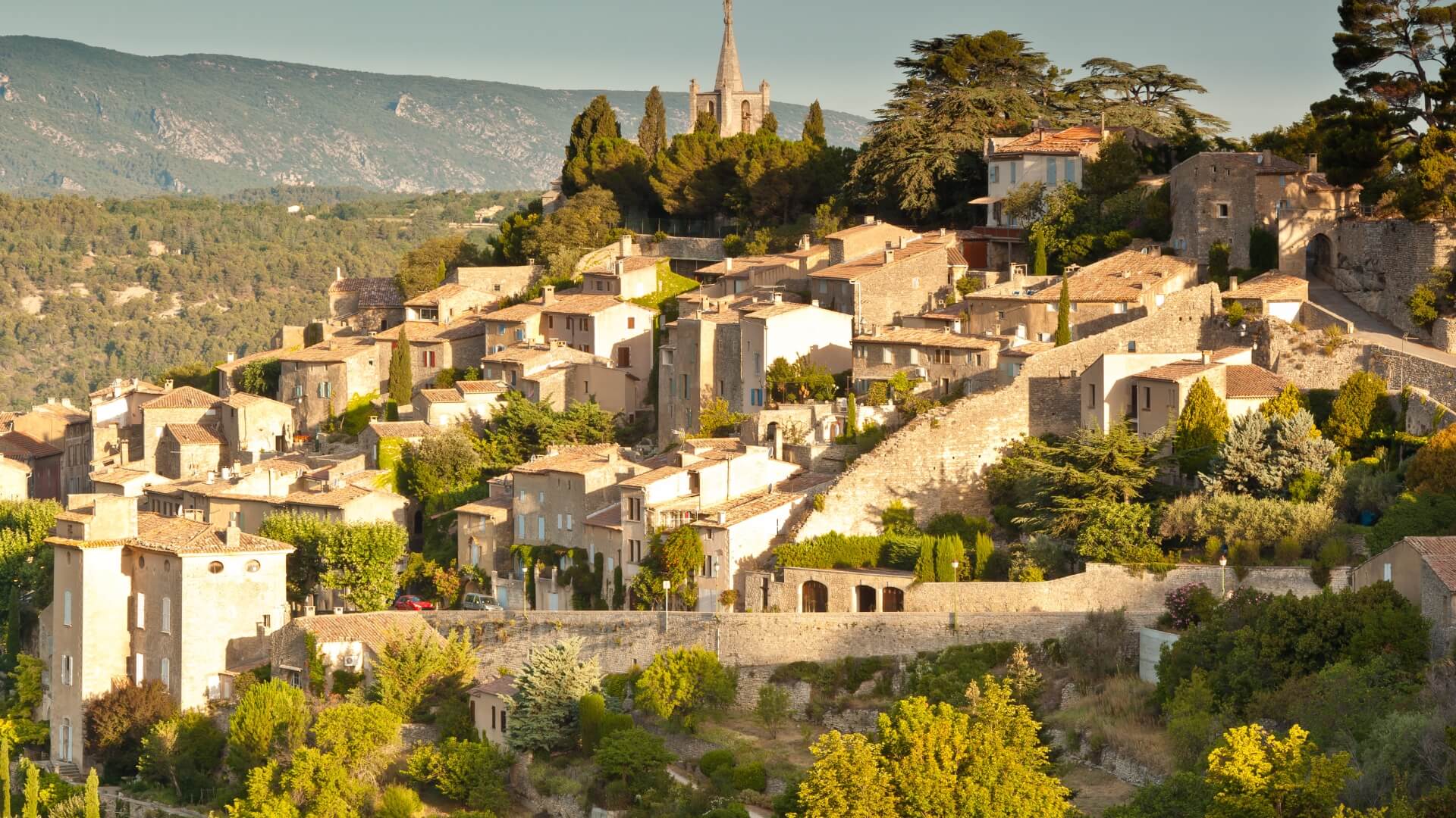 Bonnieux, a hilltop village in Provence, France, with ancient stone walls, lush Mediterranean greenery, and surrounding mountains.
