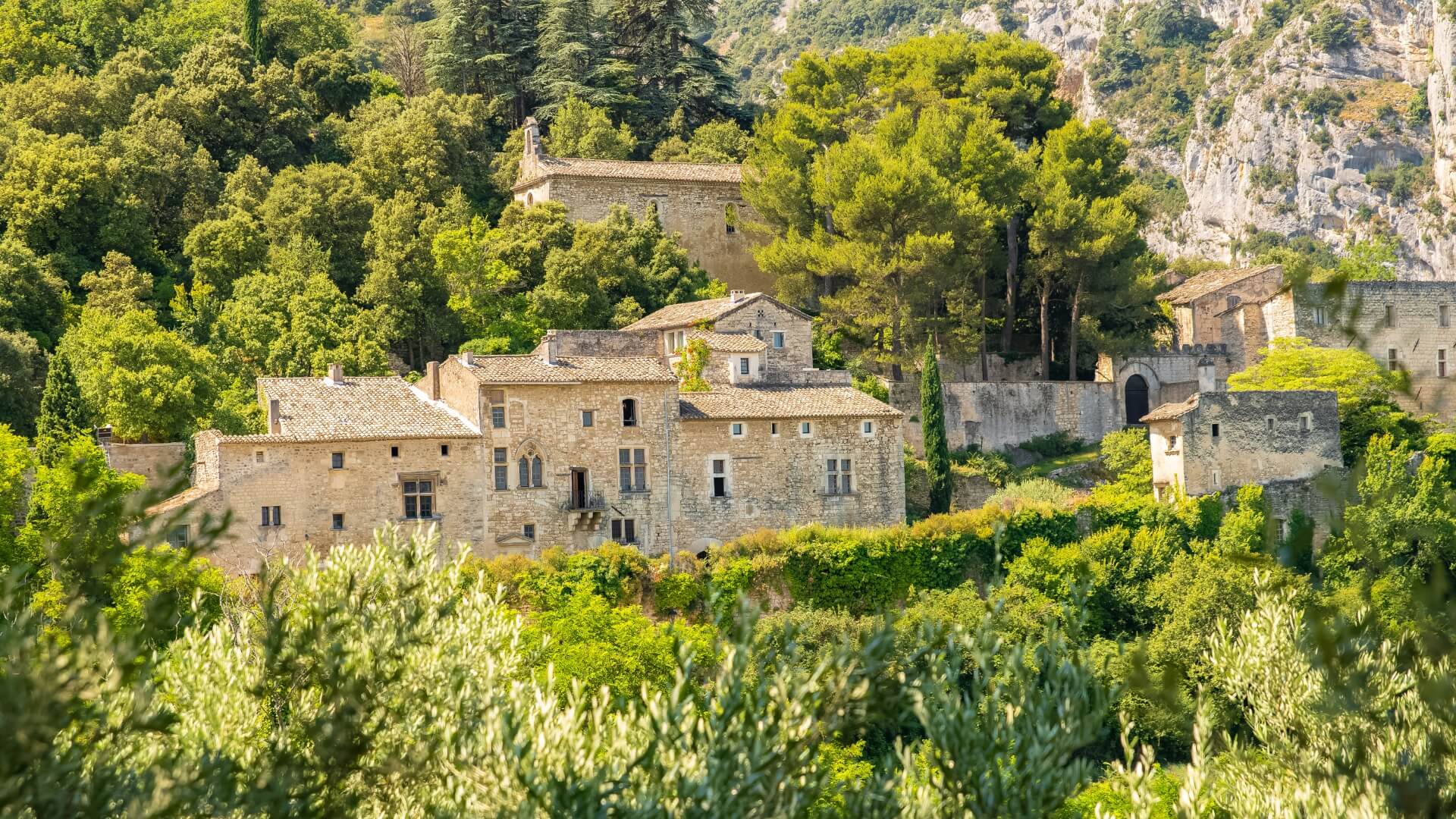 Goult, a mountainside village in Provençal France, is nestled between olive trees, natural greenery, and rugged cliffs.