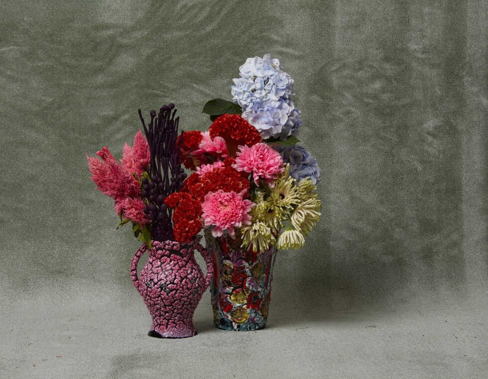 Colorful cut flowers styled in unique vases against soft background.