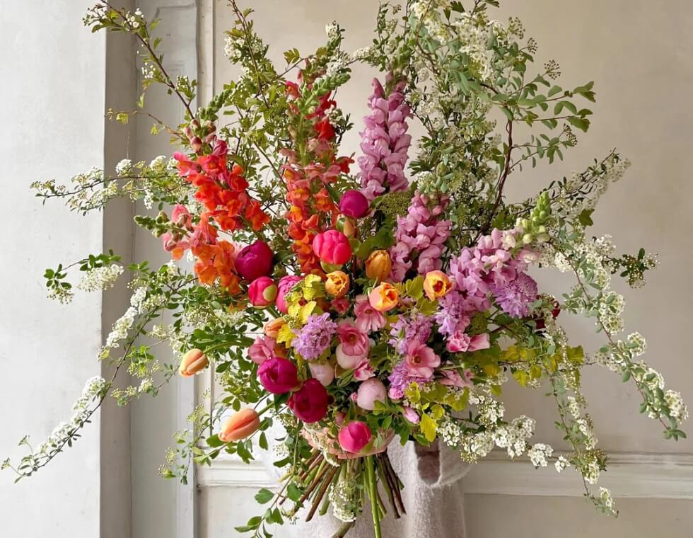 Lush bouquet of flowers with tulips, peonies, and blooming branches by Désirée Fleurs in Paris.