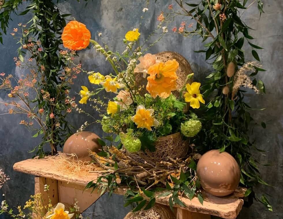 Whimsical floral display at Maison Vertumne in Paris with orange flowers, daffodils, and greenery.