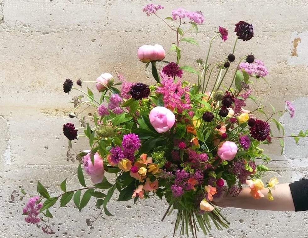 Fresh floral bouquet with pink peonies, purple accents, and greenery styled by Maison Vertumne in Paris, France.