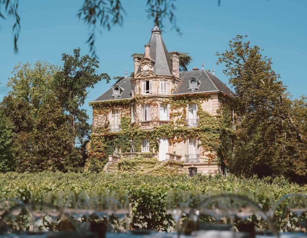 Château Carmes Haut-Brion vineyard estate in Graves, France, surrounded by lush greenery and climbing ivy.