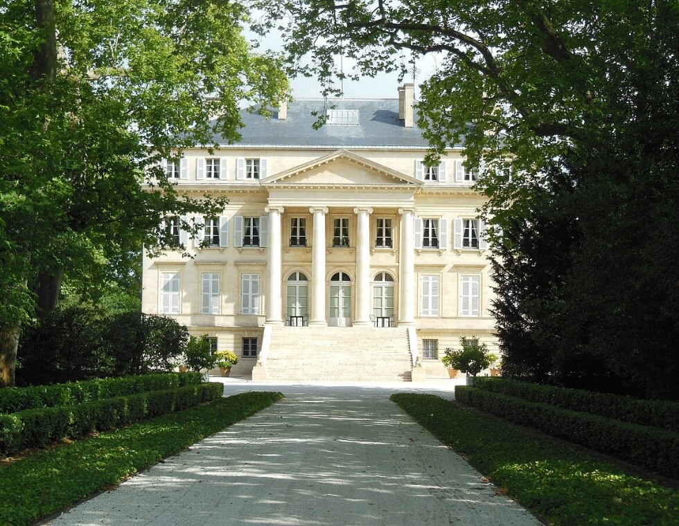 Château Margaux vineyard near Bordeaux, France, featuring white stone columns and lush green trees.