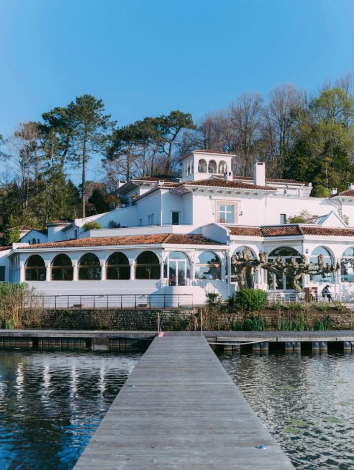 Scenic autumn view of Brindos Lake and Château hotel in France, featuring the dock and hotel facade.
