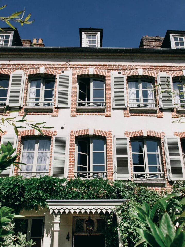 Maison de Lucie hotel in France with cozy red brick exterior and large French windows.
