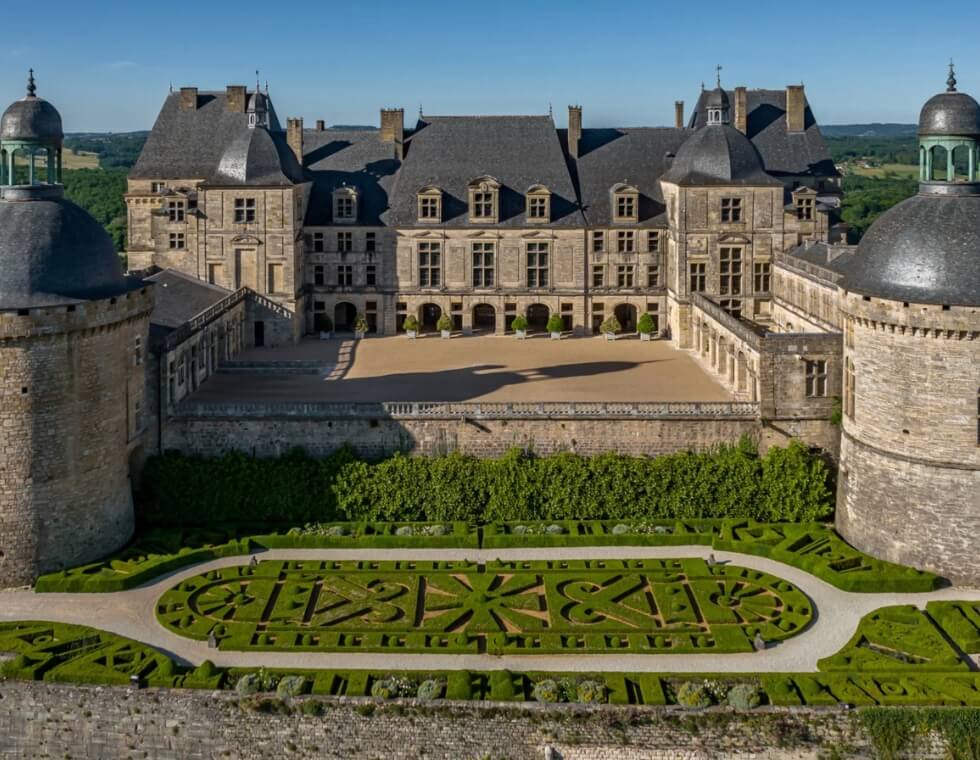 Historic Hautefort Castle in Dordogne, France, with manicured French gardens, a courtyard, and natural light.