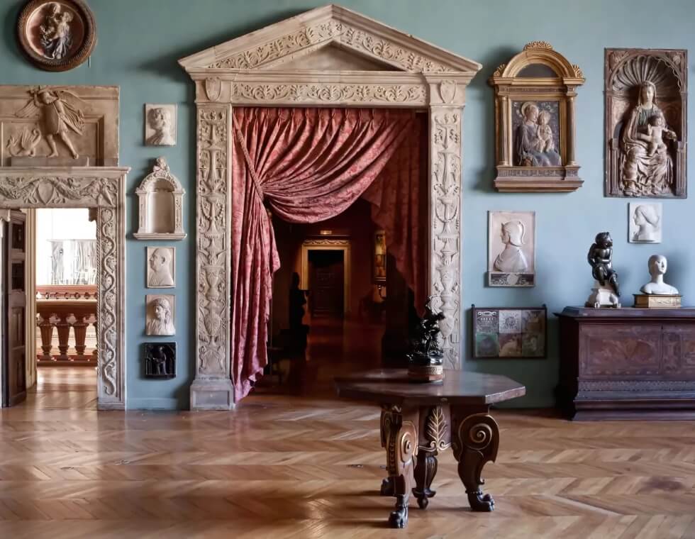 Interior of the Jacquemart-André Museum in Paris, France, featuring blue walls, historic stone frescos, and antique furniture.