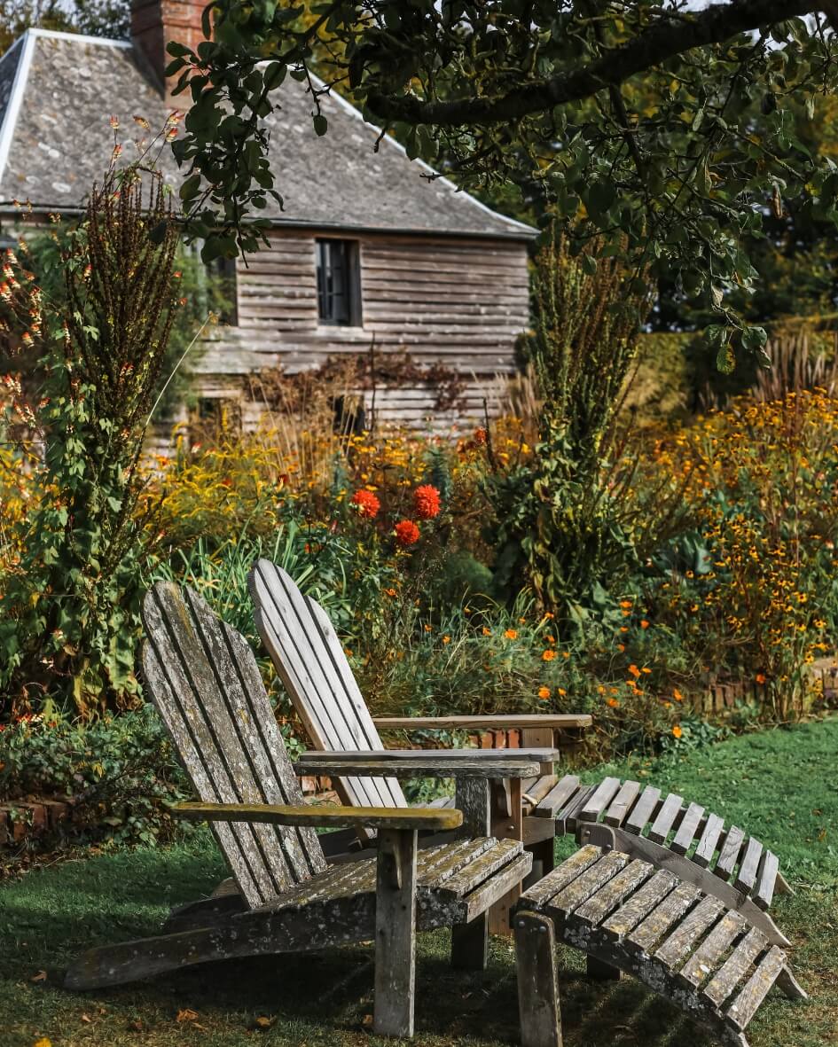 Rustic garden chaise lounges in a fall garden setting, Normandy, France.