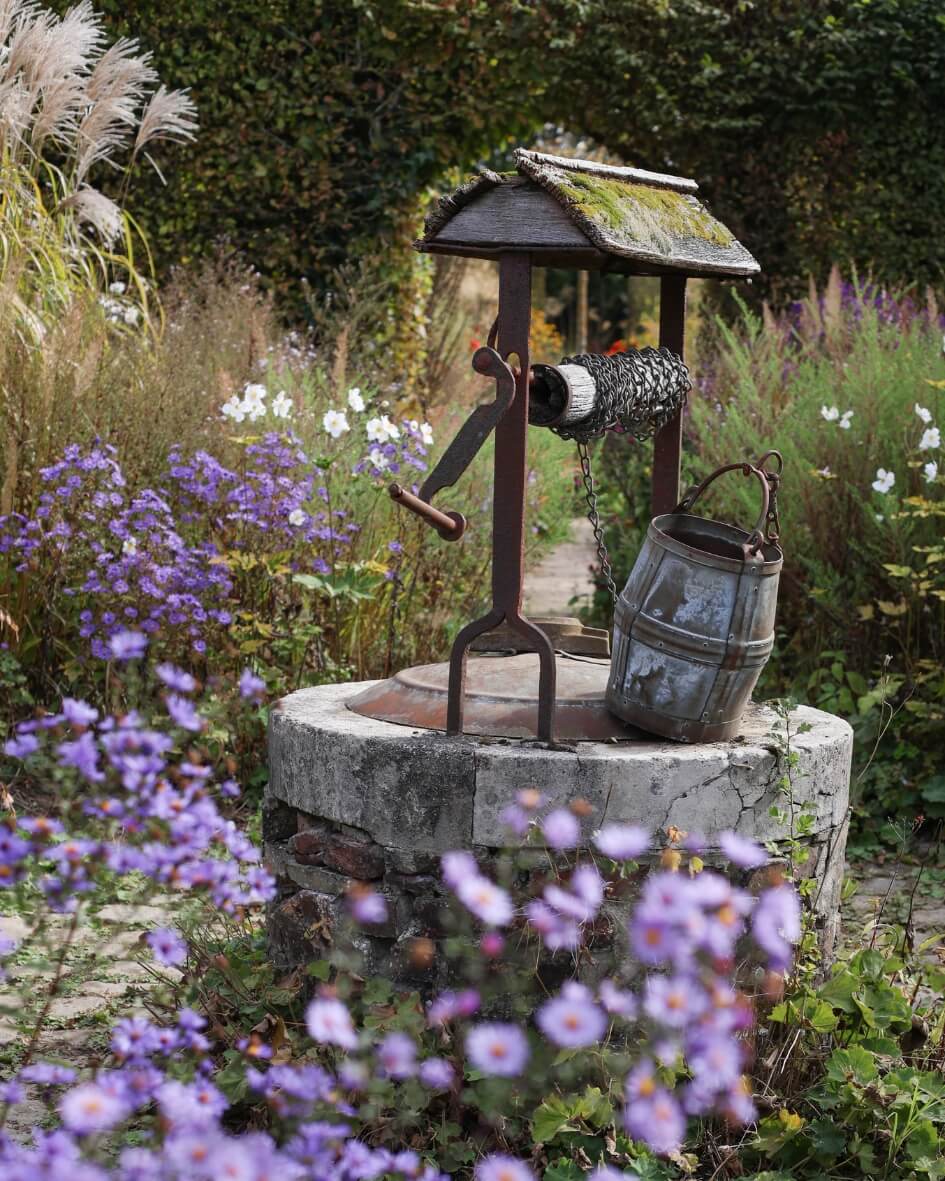Rustic garden well among blooming wildflowers in a Normandy garden, France.
