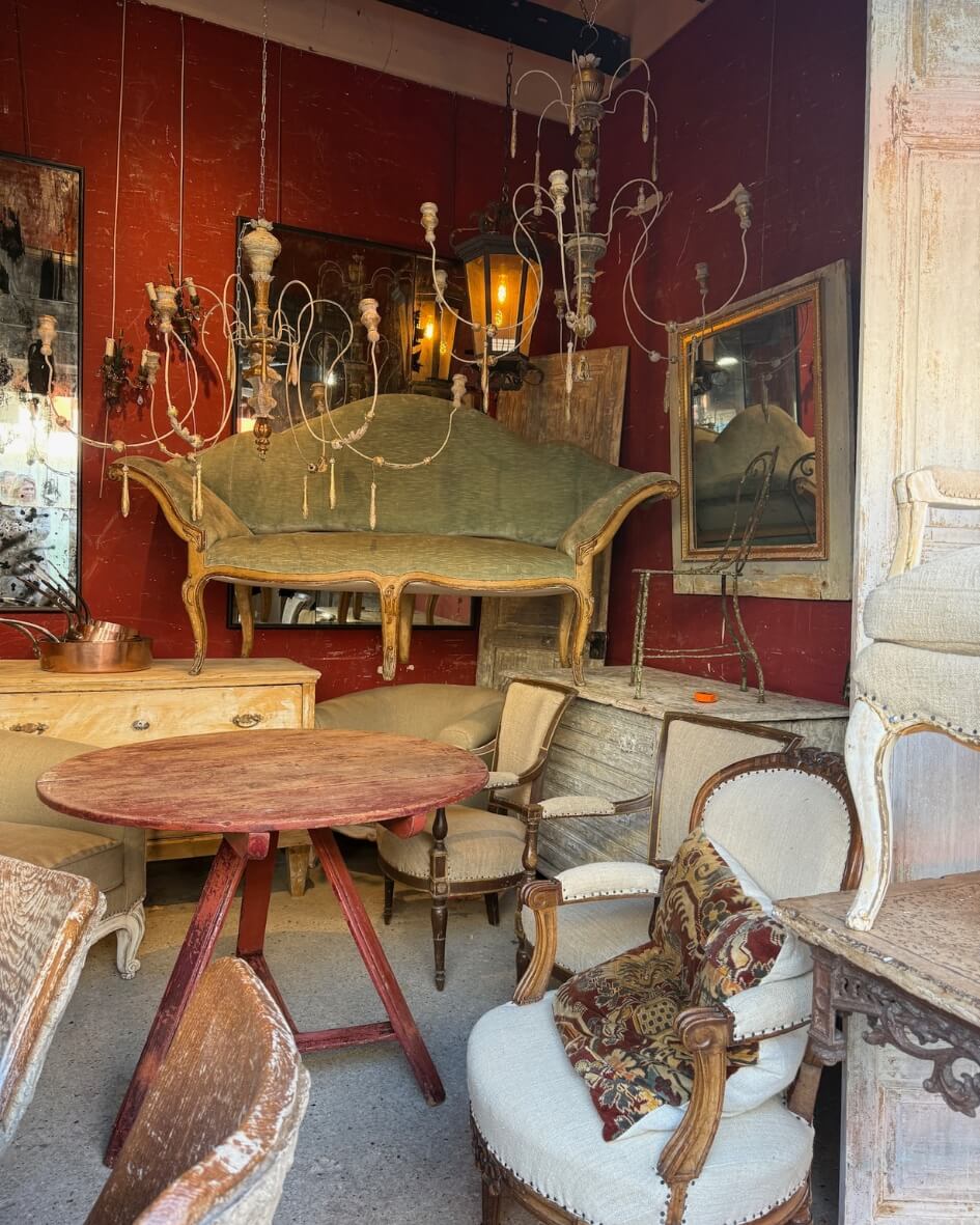 An antique shop in Normandy, France, filled with rustic furniture and chandeliers.