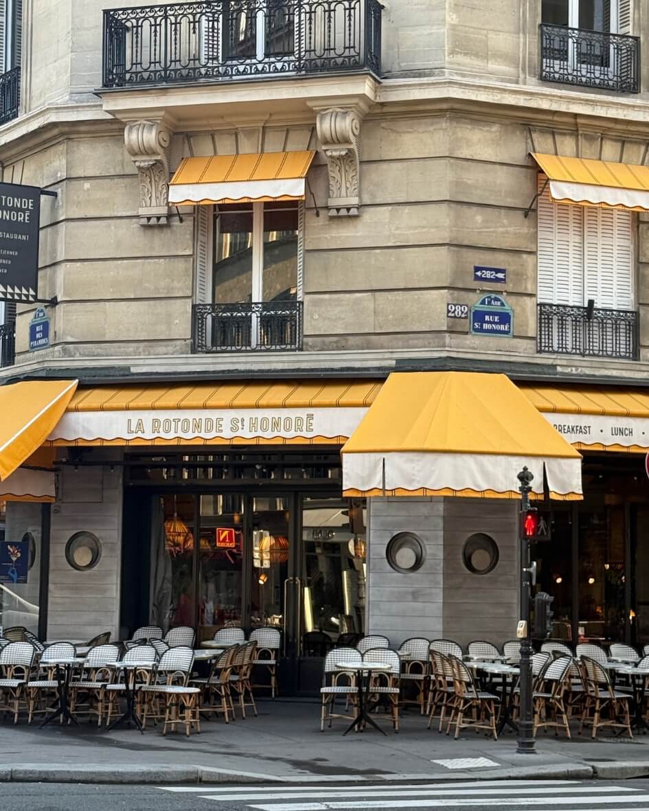 La Rotonde St. Honoré bistro with terrace seating beneath bright yellow awnings in Paris, France.