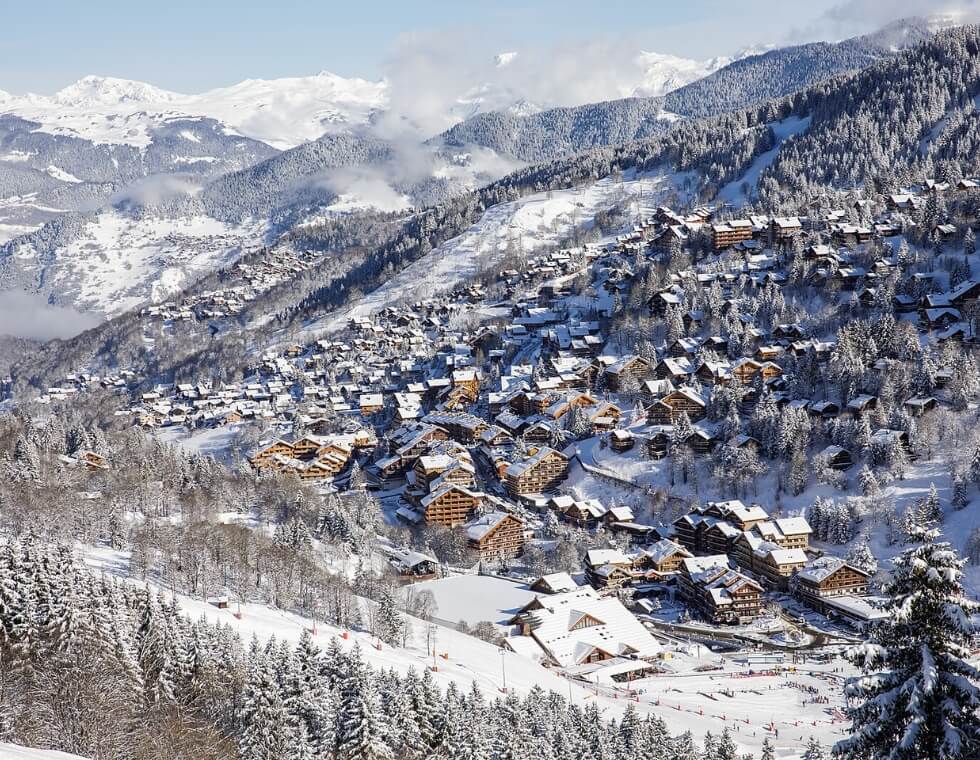 Méribel ski resort in the French Alps with chalets among evergreens and slopes.