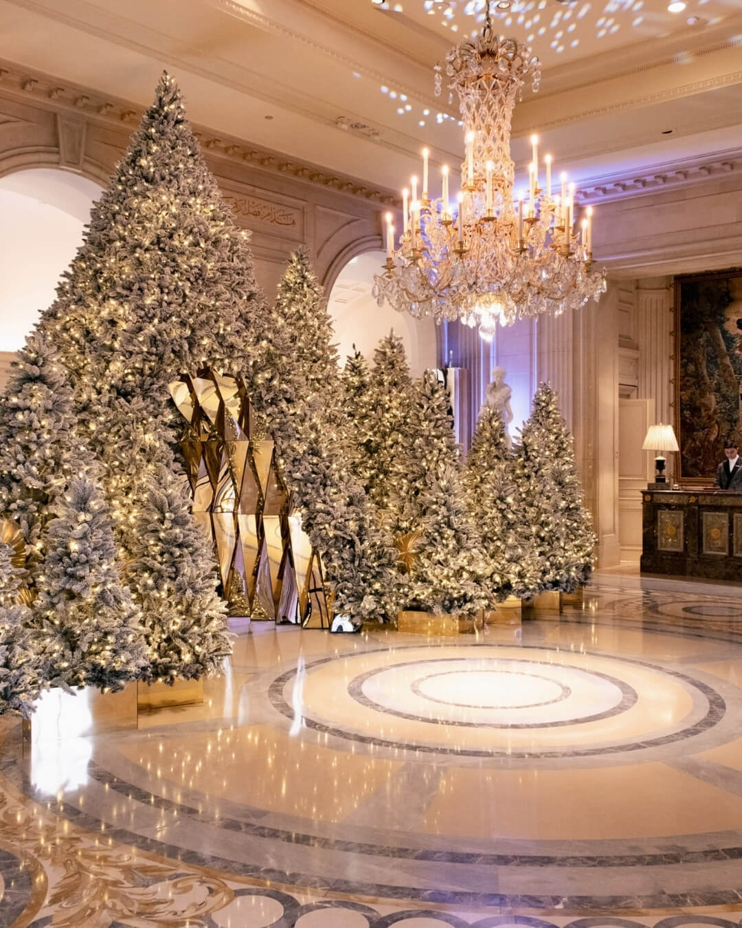 Festive ballroom at the Four Seasons Hotel George V in Paris, featuring decorated Christmas trees and a chandelier.