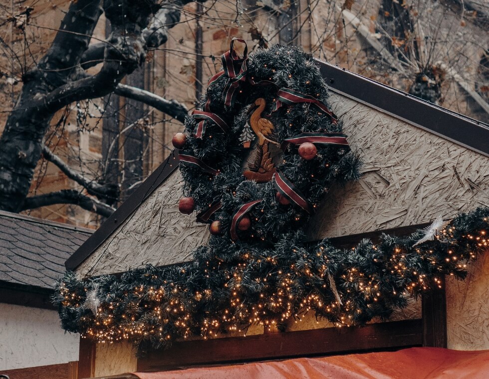 Holiday wreath mounted at a Christmas market in Reims, France with holiday garland below.