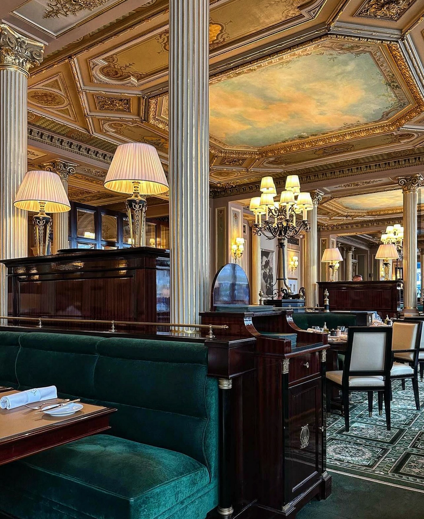 Cafe de la Paix in Paris, France featuring gold columns, elegant gold crown moulding, and plush seating.