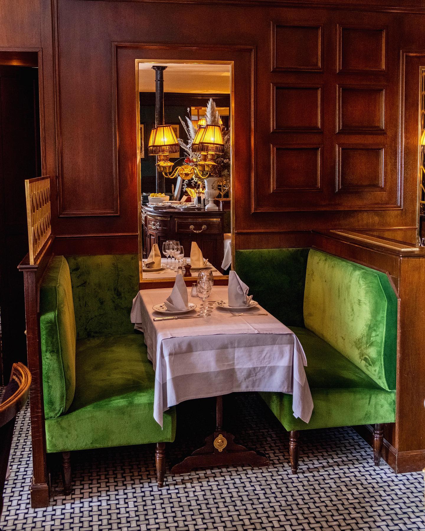 Le Voltaire restaurant in Paris, France with cozy velvet seating, wood paneling, and warm lighting.