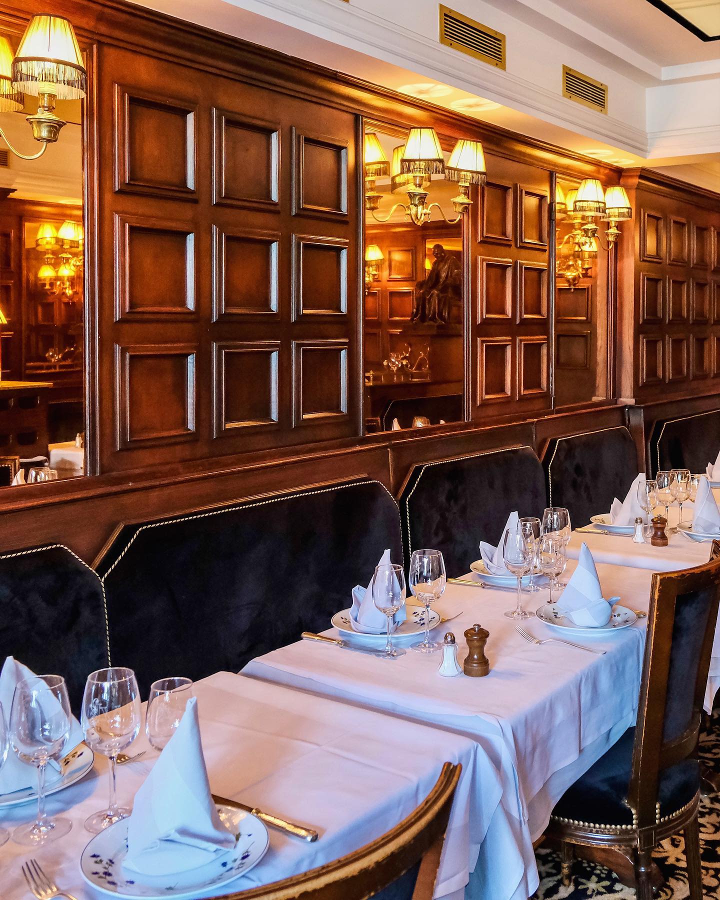 Le Voltaire restaurant in Paris, France with intimate dining tables beside elegant art deco walls, and warm soft lighting.