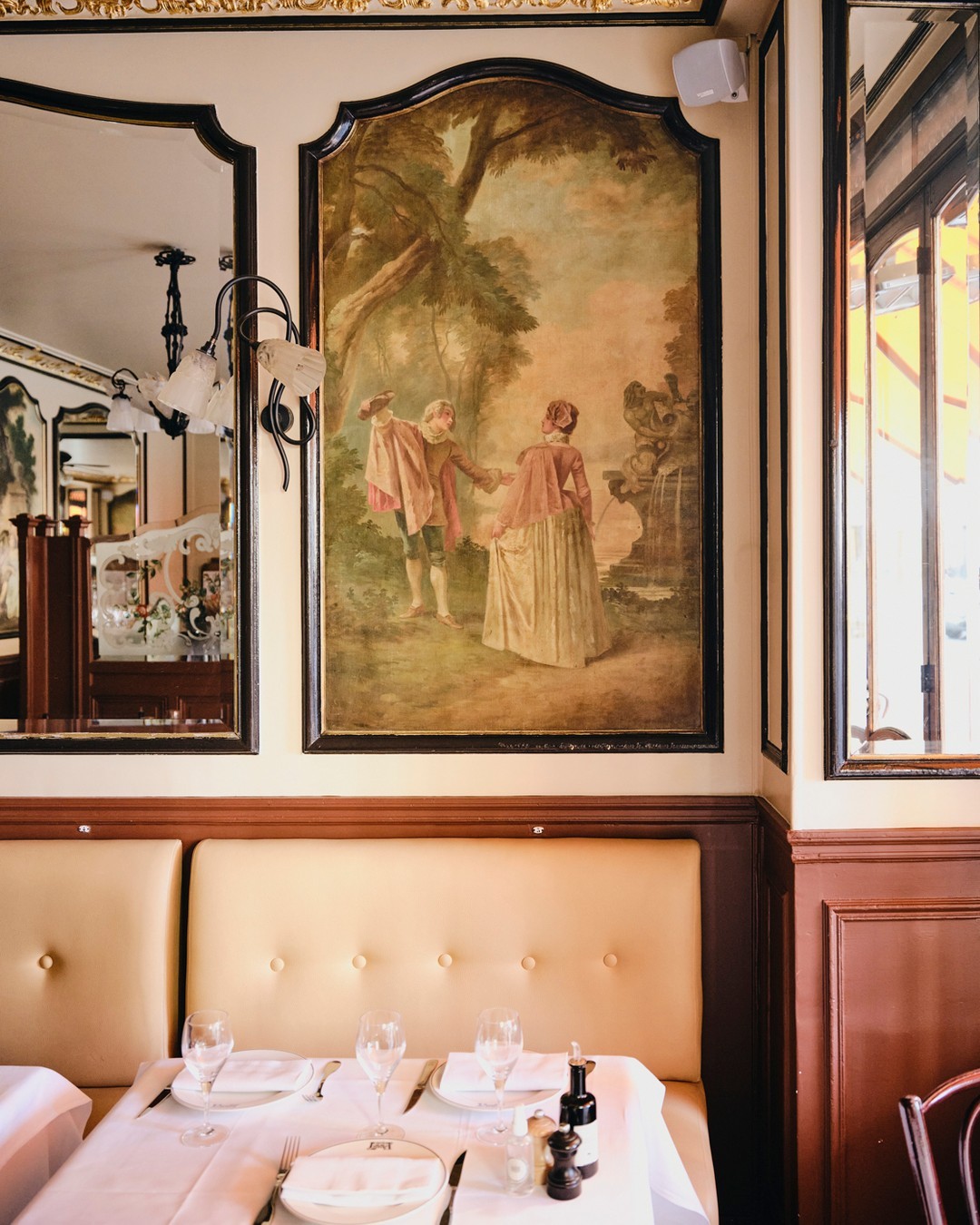 Le Petit Lutetia restaurant in Paris, France with framed frescos, art deco light fixtures, and bright natural light.