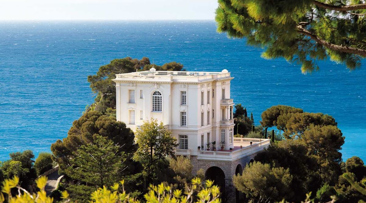 Karl Magerfeld's cliffside villa in Monaco, France beside lush greenery and the Mediterranean Sea.