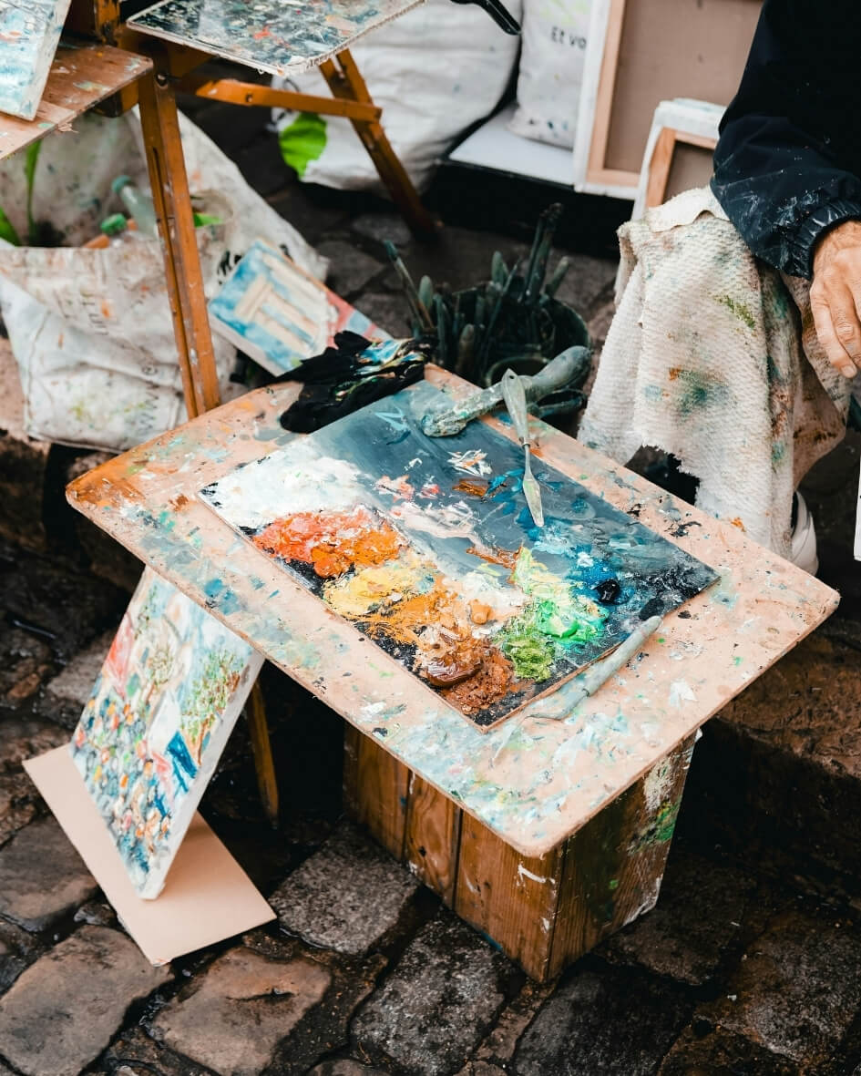 Artist pallet beside finished paintings in France.